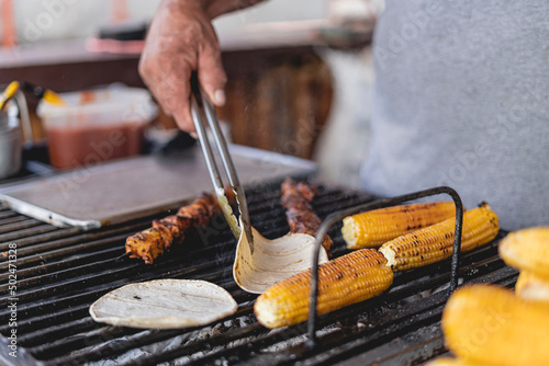 street sale of grilled corn on the cob and meat skewers