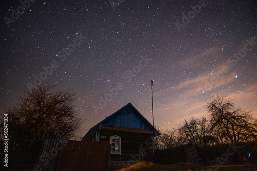 An old wooden village house on the background of the night starry sky in the countryside (country, village) in spring at night © Иван Колесенко