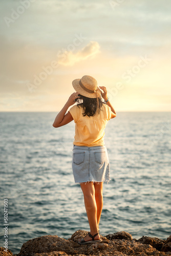 woman is standing on the rocks and looking at the sea, turned back