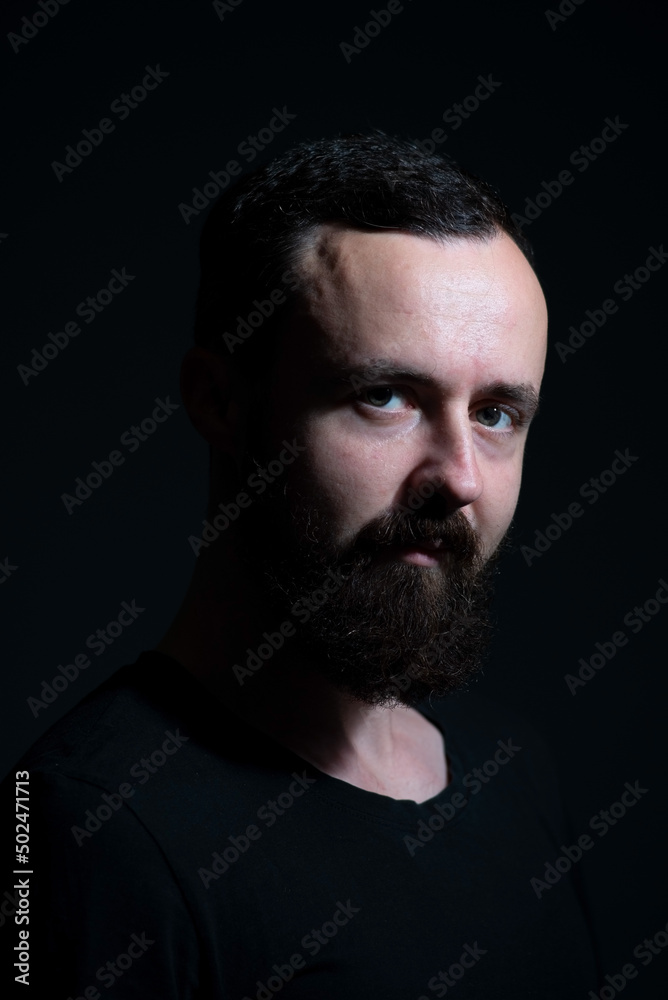 dramatic portrait of bearded millennial on black background dramatic portrait of bearded millennial on black background