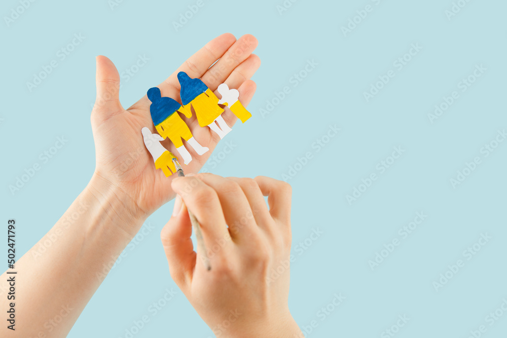 Woman hands hold a paper-cut family painted in the national colors of Ukraine. Woman hands hold a paper-cut family painted in the national colors of Ukraine.