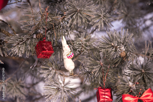 A snow-covered pine tree with Christmas toys and the symbol of the Eastern new year 2023-a hare.