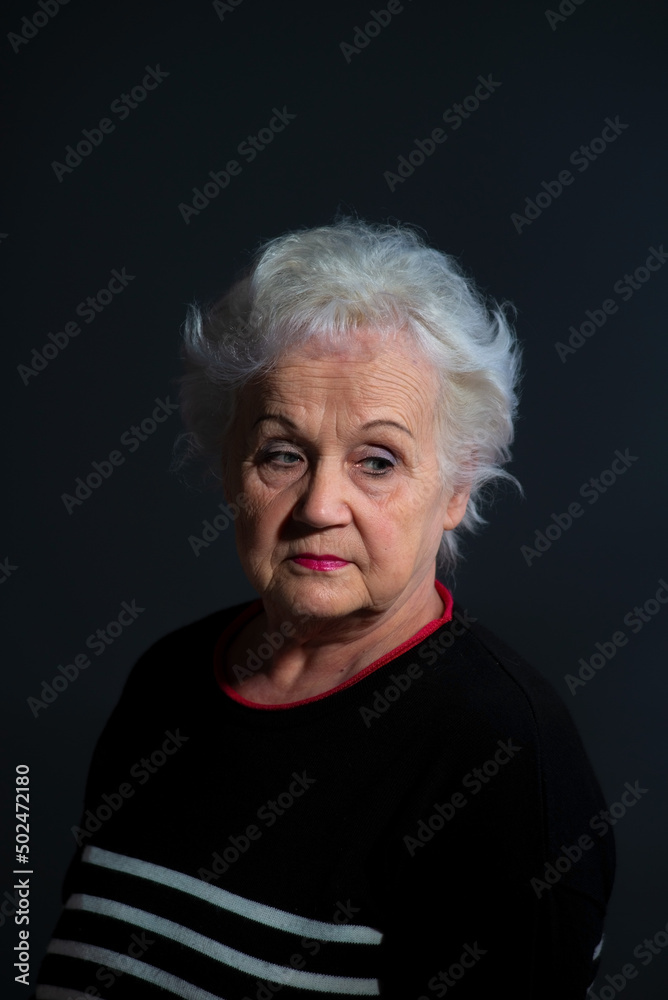 portrait of a grandmother in a dark sweater on a dark background portrait of a grandmother in a dark sweater on a dark background