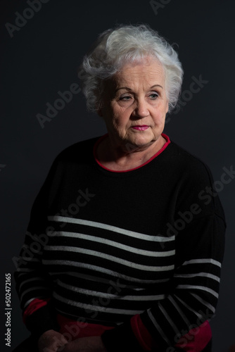 portrait of a grandmother in a dark sweater on a dark background © Алексей Доненко