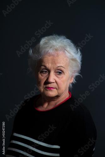 portrait of a grandmother in a dark sweater on a dark background © Алексей Доненко
