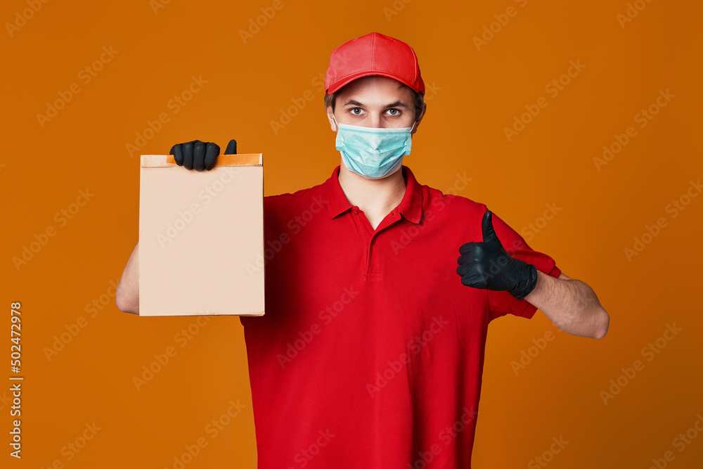 Delivery man employee in red cap face mask, empty cardboard box Delivery man employee in red cap face mask, empty cardboard box