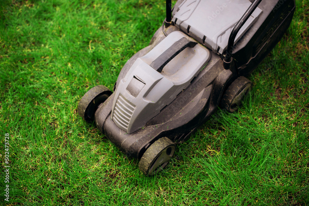 Lawn mower on green lawn in the garden Lawn mower on green lawn in the garden