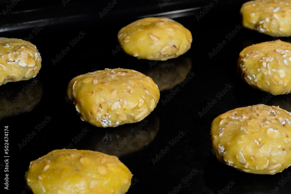 Many uncooked homemade oatmeal cookies on metal sheet in oven - close up view. Dessert, cookery, raw, baking, gastronomy and food concept Many uncooked homemade oatmeal cookies on metal sheet in oven - close up view. Dessert, cookery, raw, baking, gastronomy and food concept
