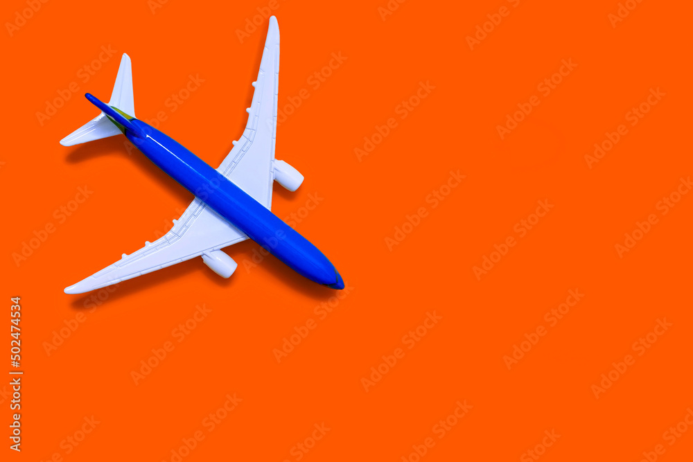 Airplane model on a orange background with free space for text or advertising. Tourism or freight transport concept. Toy airplane on a yellow background with a top view