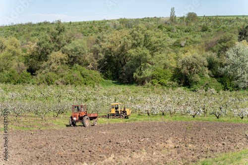 Old Tractor in the Field. Farmer in Old-fashioned tractor sowing crops at field. Woman driving small tractor in field and waving hand