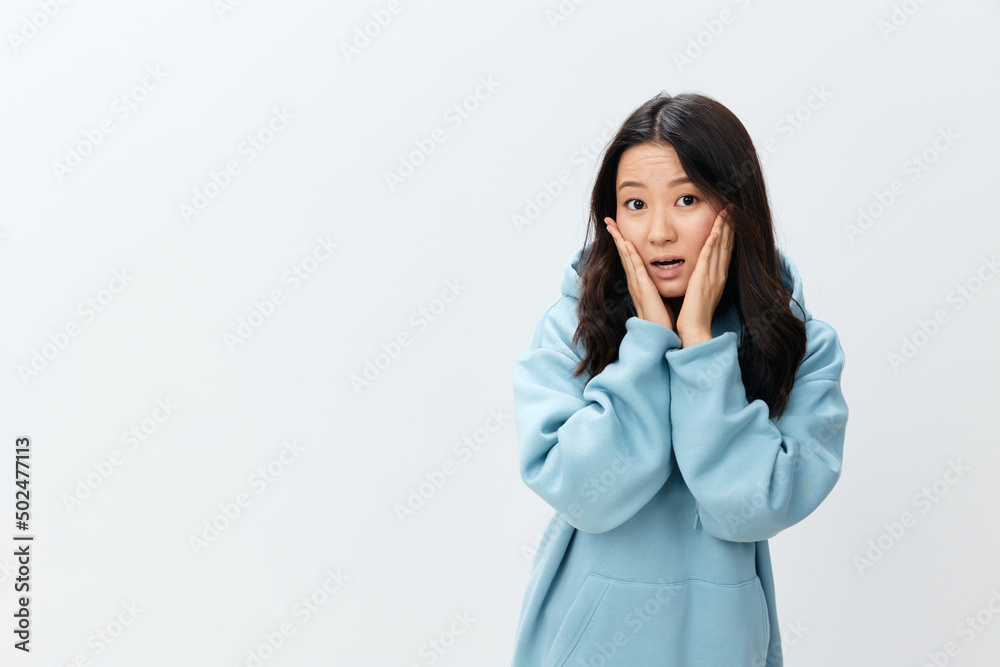 Wow. Shocked excited cute Asian young female in blue hoodie sweatshirt touches cheeks posing isolated on over white studio background. The best offer for ad. Fashion New Collection Ad concept Wow. Shocked excited cute Asian young female in blue hoodie sweatshirt touches cheeks posing isolated on over white studio background. The best offer for ad. Fashion New Collection Ad concept