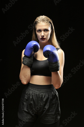 Young woman in boxing gloves against a black background