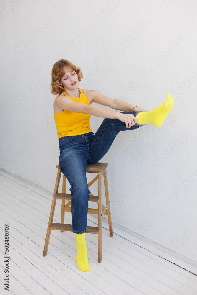Portrait of young girl in yellow socks sitting on wooden ladder