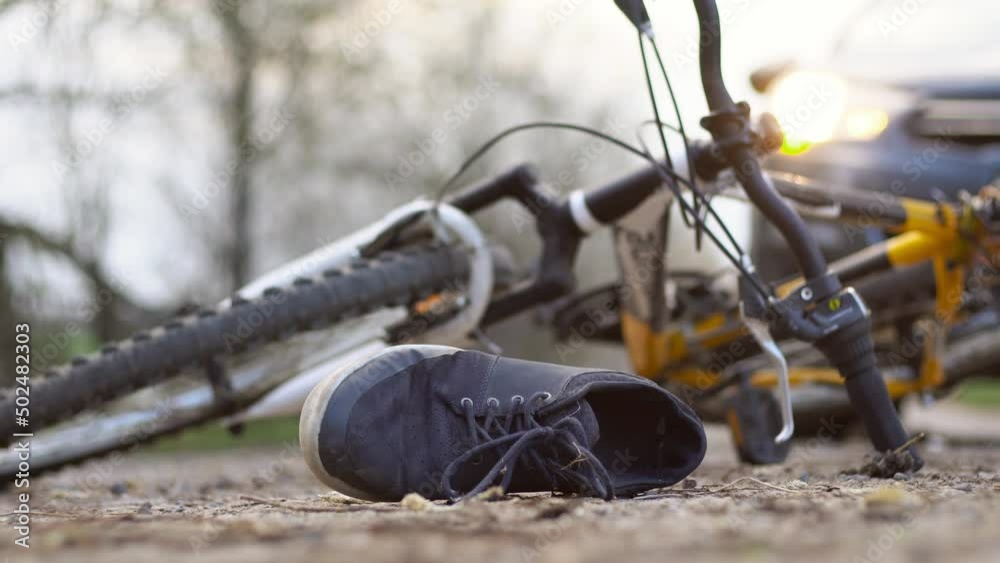 Close-up of a sneakers on the road near bicycle after car accident.