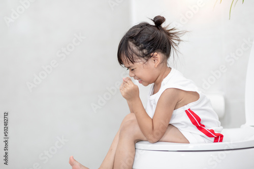 The little girl is sitting on the toilet suffering from constipation or hemorrhoid.