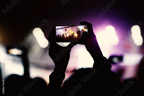 The fan taking a photo of a concert at a festival.