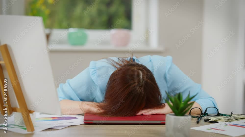 Front view exhausted Caucasian mature woman putting head on table sitting in home office indoors. Portrait of sad tired freelancer overburdened with work. Fatigue and overworking concept Front view exhausted Caucasian mature woman putting head on table sitting in home office indoors. Portrait of sad tired freelancer overburdened with work. Fatigue and overworking concept
