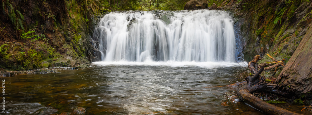 Fototapeta premium Beautiful mountain rainforest waterfall with fast flowing water and rocks, long exposure.