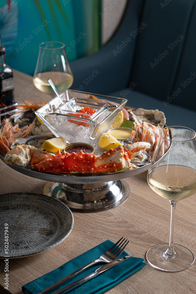 Dish with red caviar, shrimp, crab sauce and other seafood. Served with glasses of white wine in a restaurant.