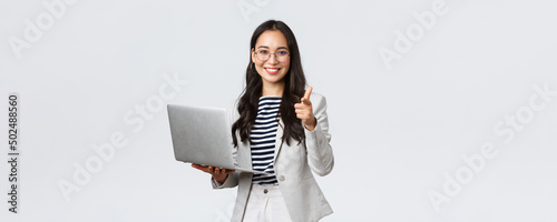 Business, finance and employment, female successful entrepreneurs concept. Smiling pleased businesswoman praise coworker who made good point, pointing finger camera satisfied, hold laptop