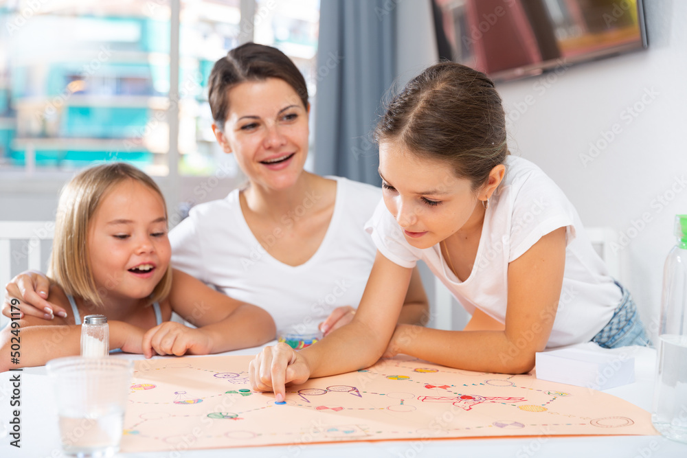 Happy single mother with two daughters playing board games and having fun