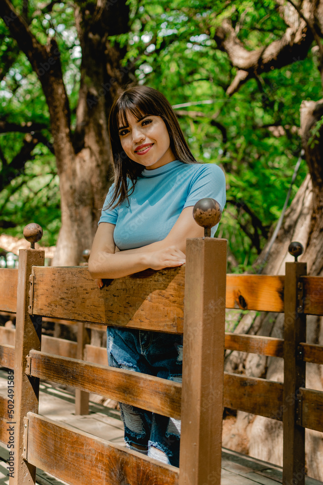 Mujer sonriendo recargada en un puente de madera Mujer sonriendo recargada en un puente de madera