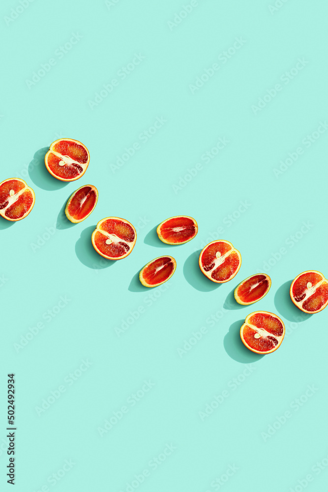 Citrus red orange fruit as creative background, slices of orange with hard shadows at sunlight on pastel mint background with copy space. Healthy fruits food concept. Flat lay, top view - obrazy, fototapety, plakaty 