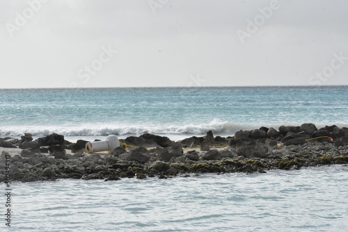 buoy on rocky pier by ocean coastline with waves crashing in and splashing against the coast photo