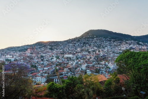 City in the evening light mountainside with colonial architecture, many white houses with tiles. Evening sky. The cramped streets of Taxco in Mexico