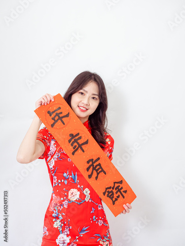 Young asian woman wearing traditional cheongsam qipao dress hold Chinese festival couplet to celebrate new year with word meaning 