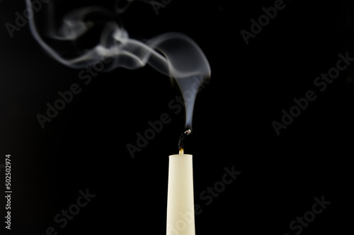 White candle extinguished on black background