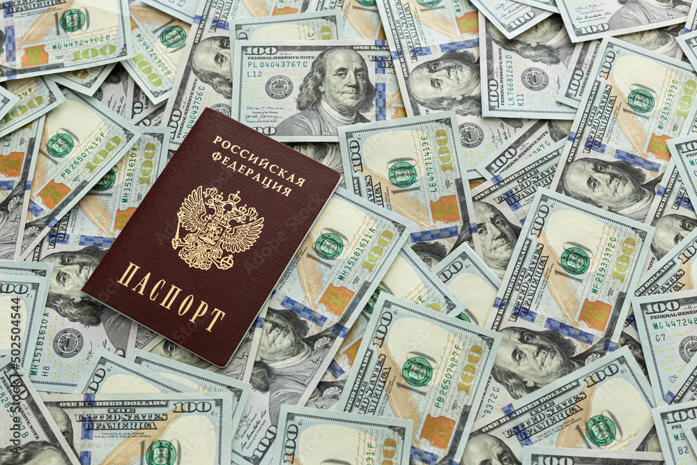 The passport is lying on a pile of hundred dollar bills. Documents and money