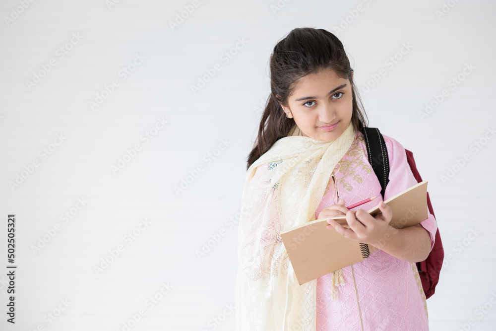 cute Indian girl smiling and writing on notebook for learning, education concept cute Indian girl smiling and writing on notebook for learning, education concept