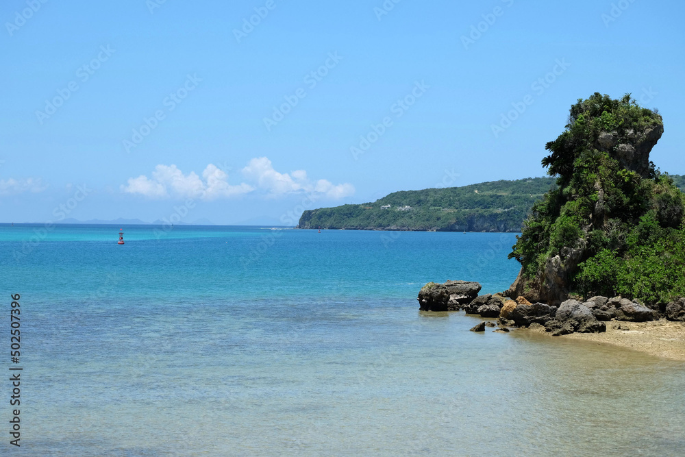Fototapeta premium 透き通るような青い海と夏の青い空、近くの小さい島と遠くの木々に囲まれた島