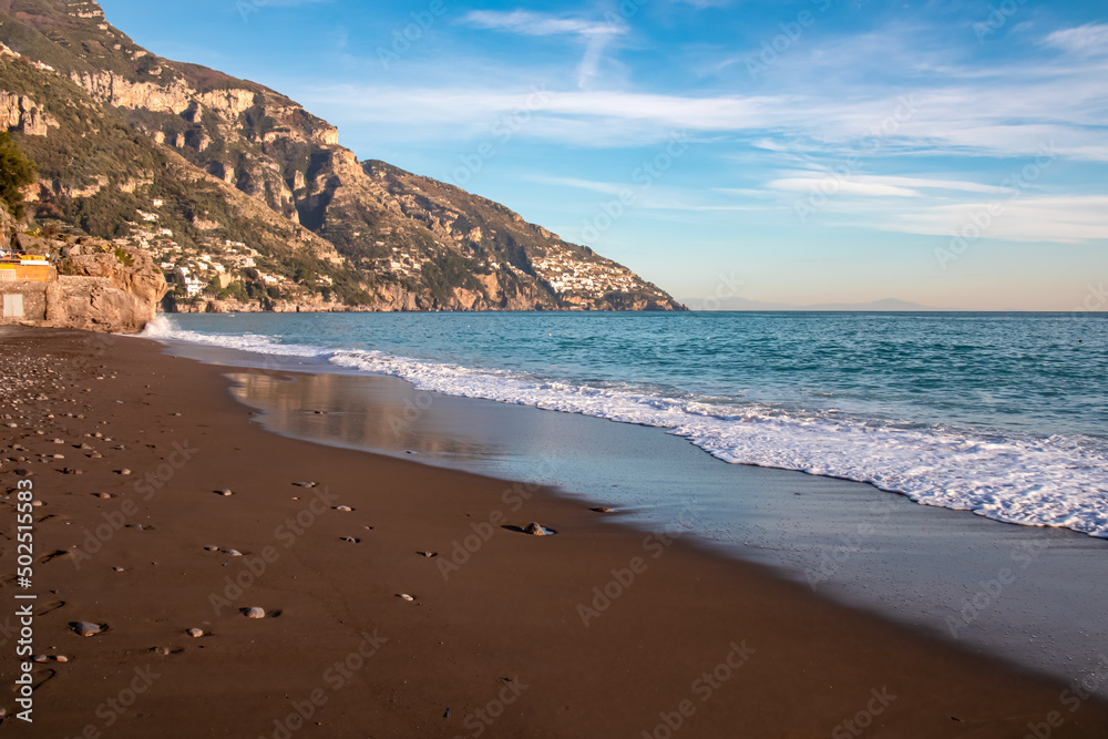 Fototapeta premium Panoramic twilight view at Fornillo Beach in town Positano, Amalfi Coast, Italy, Campania, Europe. Luxury vacation Tyrrhenian, Mediterranean Sea. Early evening sunbeam reflection in sand. No people