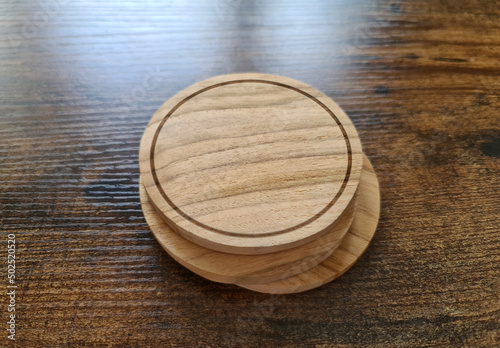Blank coaster stack mockup with wood texture on wooden surface. Circular drink pad pile template