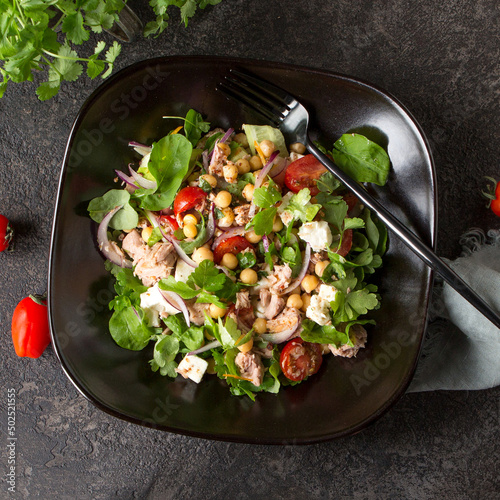 plate with salad with tuna, chickpeas and feta on a dark table