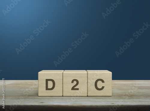 Fotografia D2C acronym on wood block cubes on wooden table over light blue gradient backgro