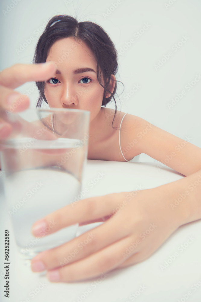 Beauty Asia girl with a great skin texture posing with a glass of water in the white background. Beauty Asia girl with a great skin texture posing with a glass of water in the white background.
