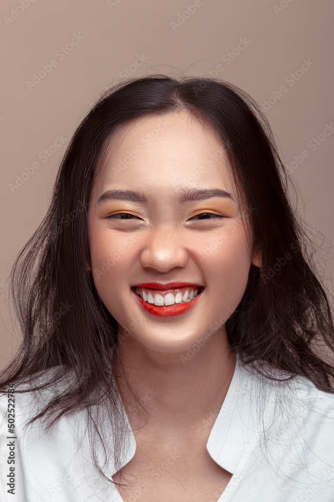 Portrait of cheerful laughing Asian woman with attractive appearance. Isolated on brown background Portrait of cheerful laughing Asian woman with attractive appearance. Isolated on brown background