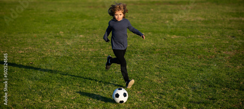 Young boy kicks the soccer ball. Football player in motion, boy in movement. Kid playing soccer, happy child enjoying sports football game, kids activities, little soccer player. © Volodymyr