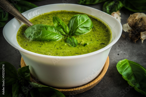 Basil pesto with a small white bowl, many fresh basil leaves, and garlic photo