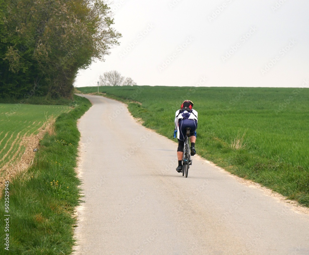 cycliste amateur roulant sur un chemin de campagne au milieu des champs