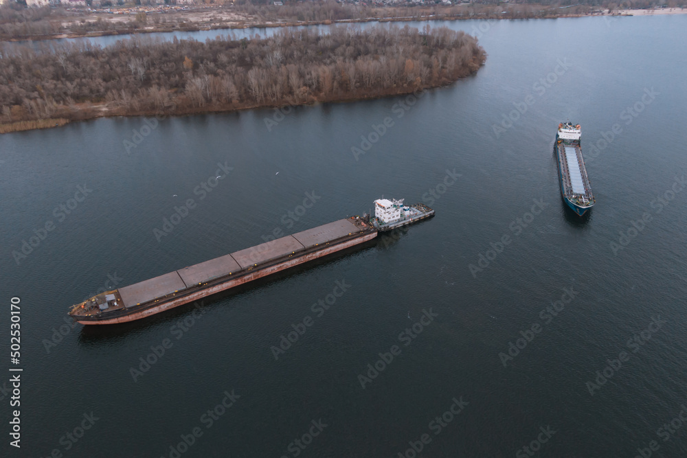 The cargo ship arrives at the river port. View from above. Panoramic view of the city. Barge floating on the Dnieper River, Ukraine. Bird's-eye view.