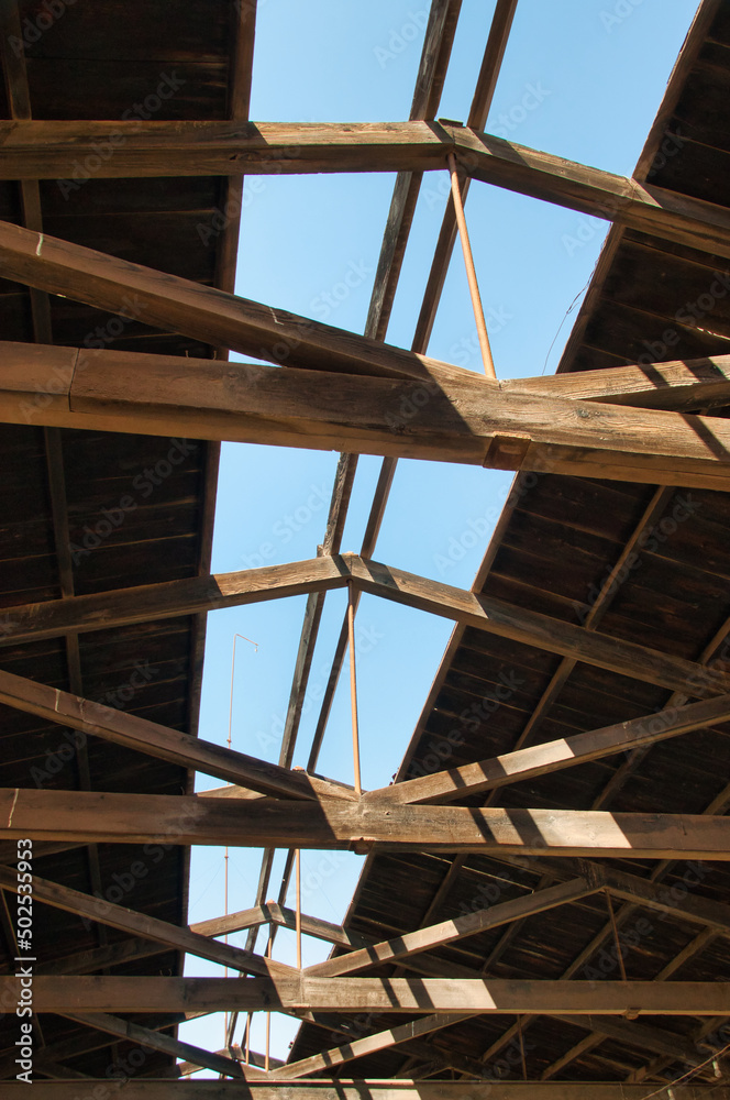 Abstract picture of a wooden roof structure with view on the clear blue sky and sunlight bursting trough creating a feeling of openess and opportunities.  