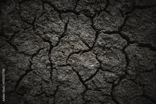 Foto Black dried cracked earthen soil, background texture