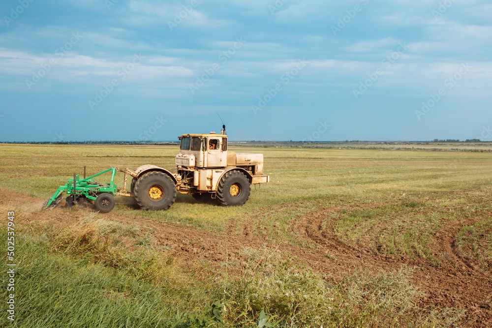 Tractor cultivating field. Plowing fields. Preparing land for sowing. Rich harvest concept.