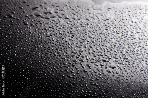 Dark shiny surface with droplets. Close up image of wet shiny background.