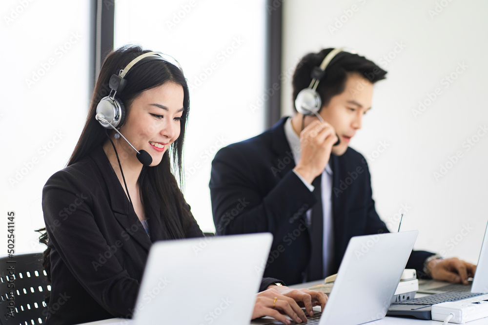 Business woman using headset phone in a call centre. Team of business people working for communication and consulting people at customer service office. Business woman using headset phone in a call centre. Team of business people working for communication and consulting people at customer service office.