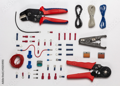 Top view of electrical tools and terminal lugs on white background
